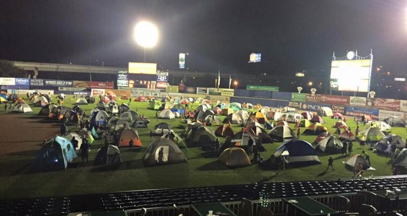 Dozes of tents set up inside a sports stadium at night