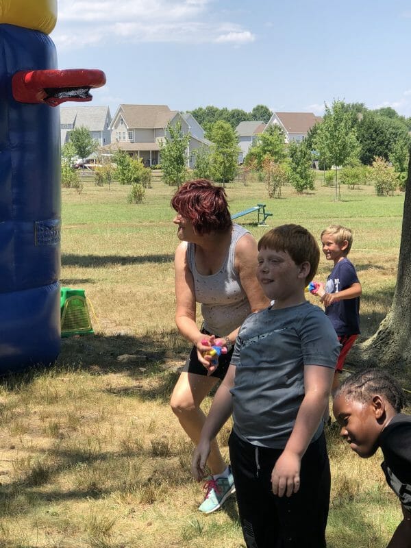 Woman getting prepared to throw wet sponge while playing with kids