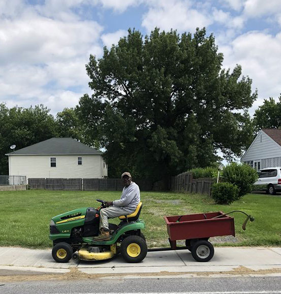 Man riding a mower down a sidewalk
