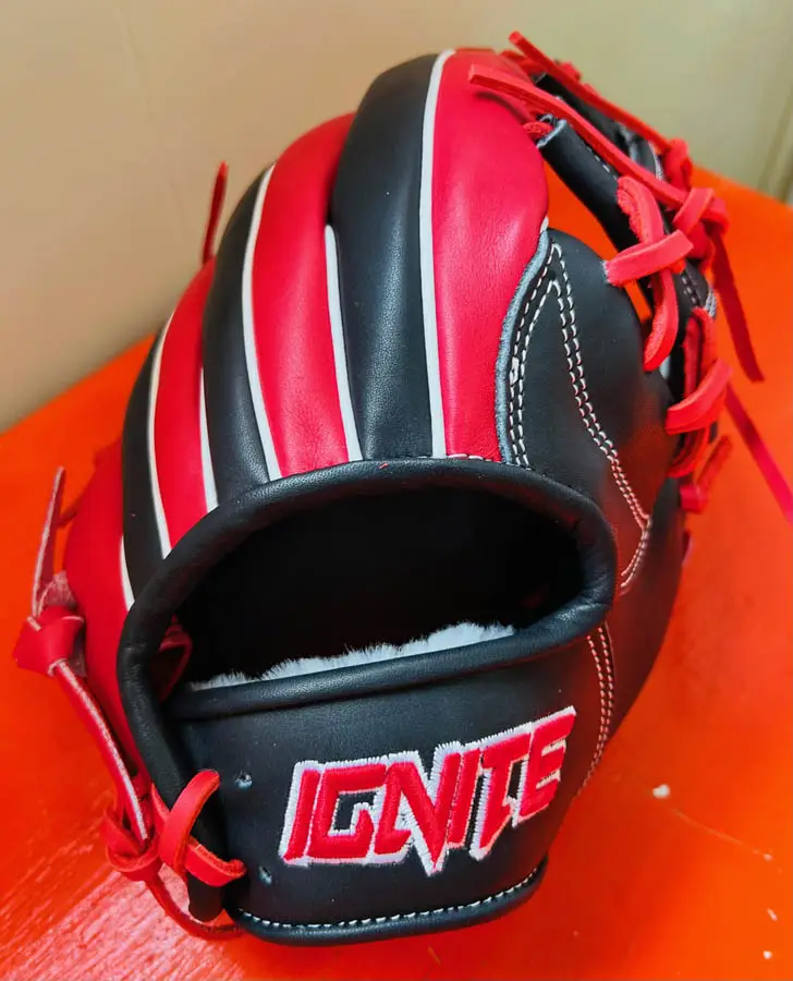 Top view of red and black baseball mitt on red table